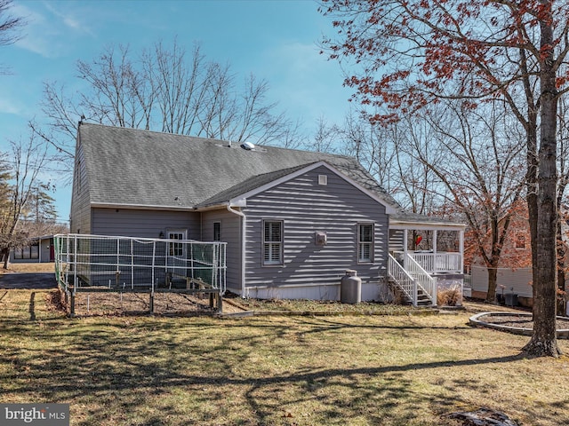 back of property featuring roof with shingles and a yard