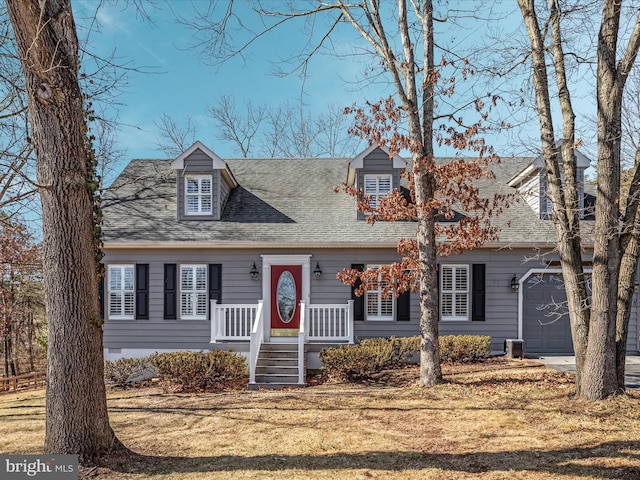 cape cod home with driveway, an attached garage, and a front yard