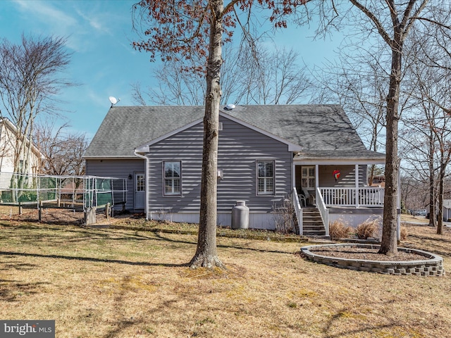 exterior space featuring covered porch, a shingled roof, and a front yard