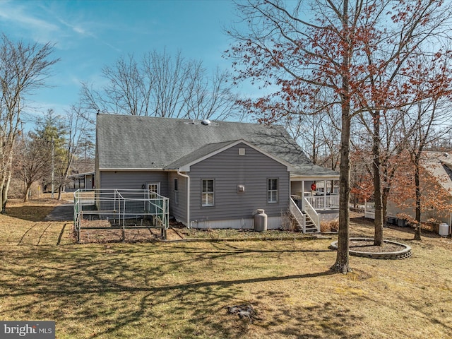 rear view of house with stairs, a porch, a lawn, and a shingled roof