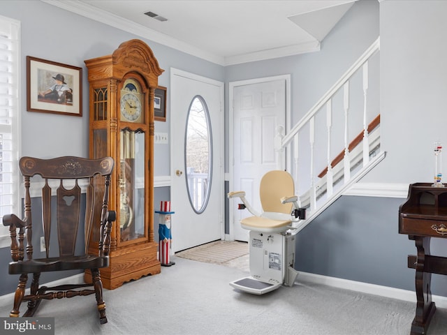 carpeted entrance foyer with visible vents, crown molding, baseboards, and stairs