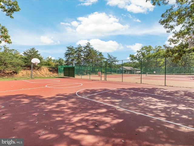 view of sport court featuring a tennis court, community basketball court, and fence