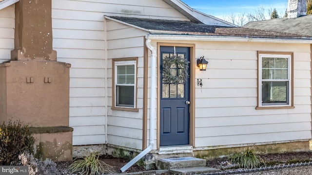 view of exterior entry with a shingled roof