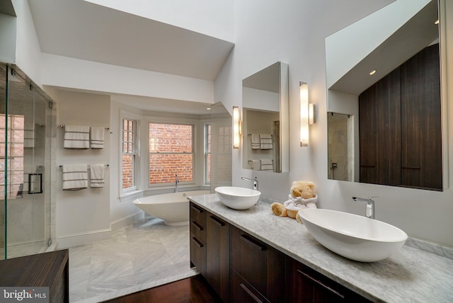 full bath with a shower stall, a freestanding tub, double vanity, and a sink