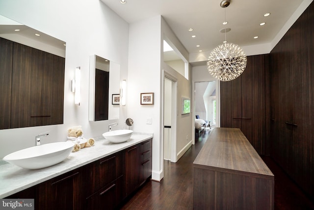 ensuite bathroom with connected bathroom, wood finished floors, recessed lighting, and a sink