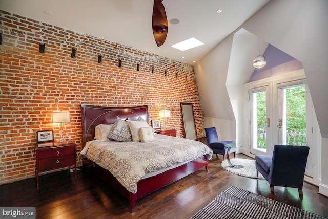 bedroom featuring access to exterior, brick wall, an accent wall, vaulted ceiling with skylight, and wood finished floors