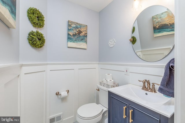 bathroom with toilet, a wainscoted wall, visible vents, and vanity