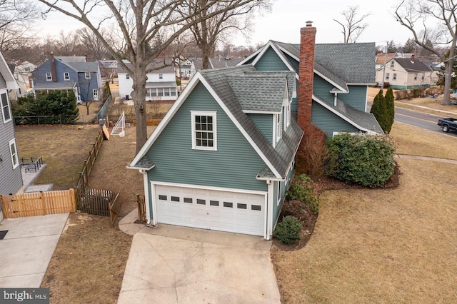 view of home's exterior with a yard, a shingled roof, fence, a residential view, and driveway