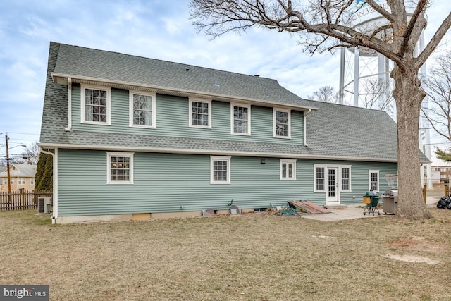 rear view of house with roof with shingles, fence, a yard, a patio area, and central AC