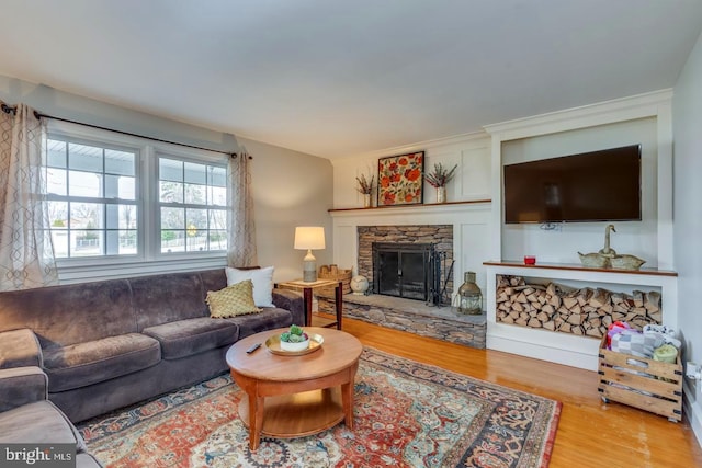 living room featuring a stone fireplace and wood finished floors