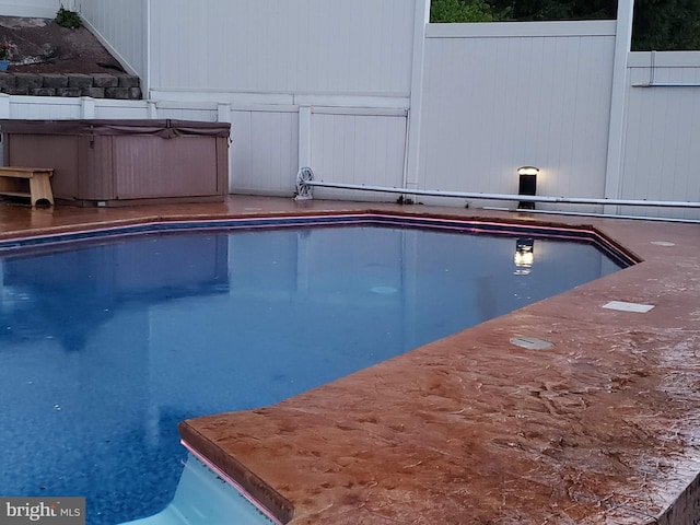 view of pool featuring a fenced in pool, fence, and a hot tub