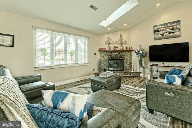 living room featuring a fireplace, recessed lighting, visible vents, lofted ceiling with skylight, and wood finished floors