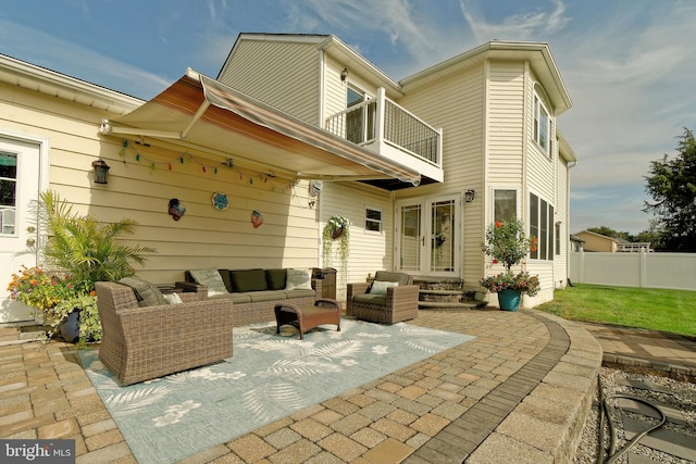 rear view of property featuring entry steps, a balcony, fence, an outdoor living space, and a patio area