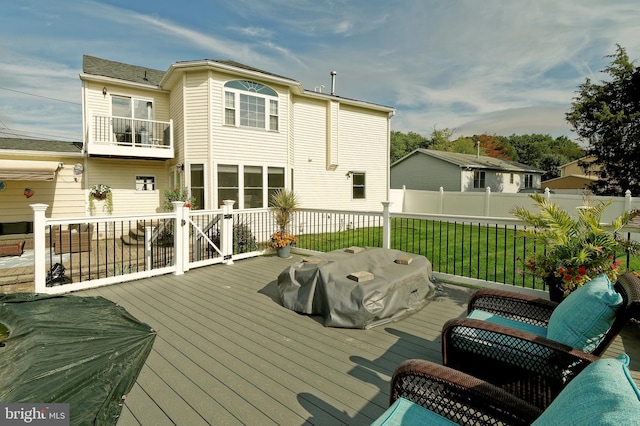 rear view of property with a lawn, fence, and a balcony