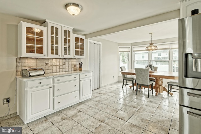 kitchen with glass insert cabinets, tasteful backsplash, white cabinetry, and stainless steel refrigerator with ice dispenser