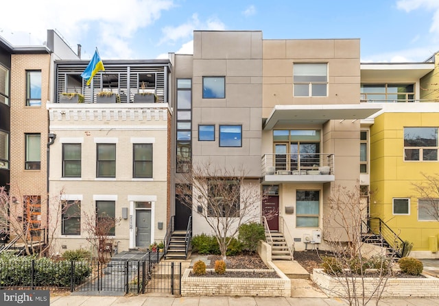 multi unit property featuring stairs, fence, and stucco siding