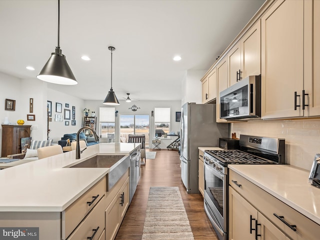 kitchen featuring dark wood-style floors, a sink, open floor plan, appliances with stainless steel finishes, and tasteful backsplash