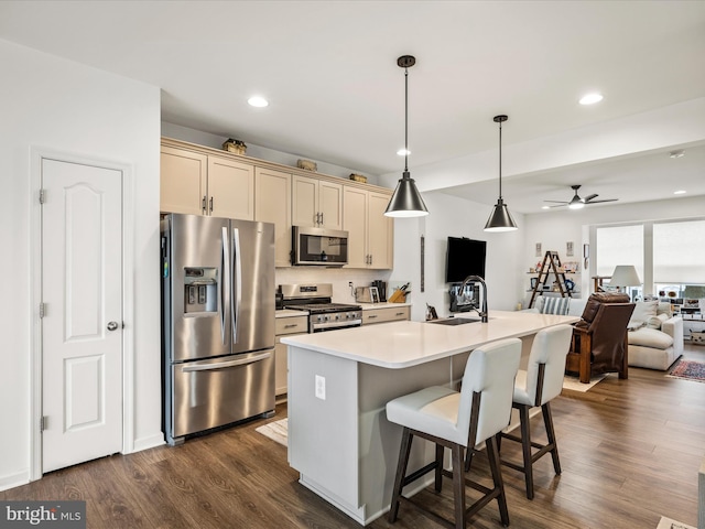 kitchen with a sink, open floor plan, stainless steel appliances, light countertops, and dark wood-style flooring