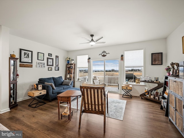 living room featuring baseboards, dark wood-type flooring, and ceiling fan