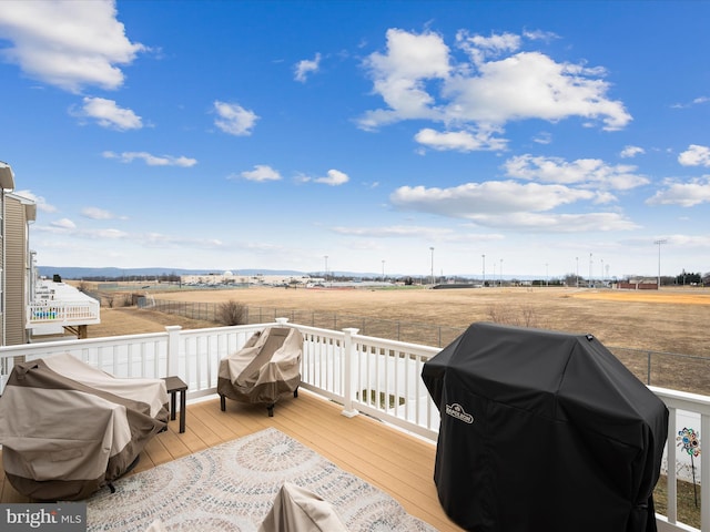 deck with area for grilling and a rural view