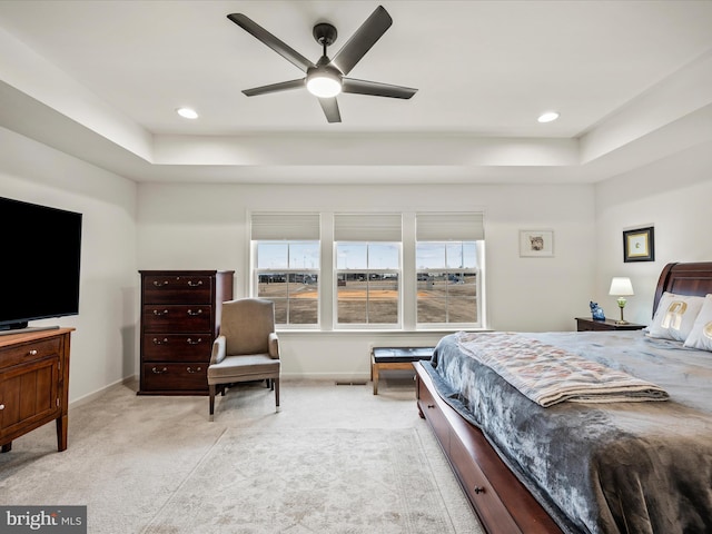 bedroom with a raised ceiling, light colored carpet, and baseboards