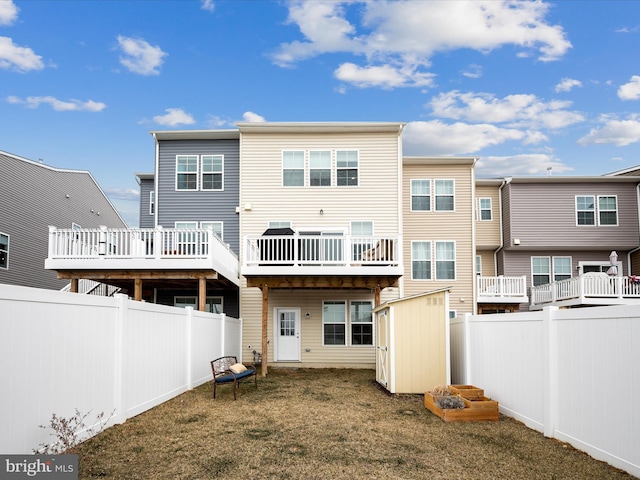 back of house featuring a fenced backyard, an outbuilding, a storage shed, and a yard