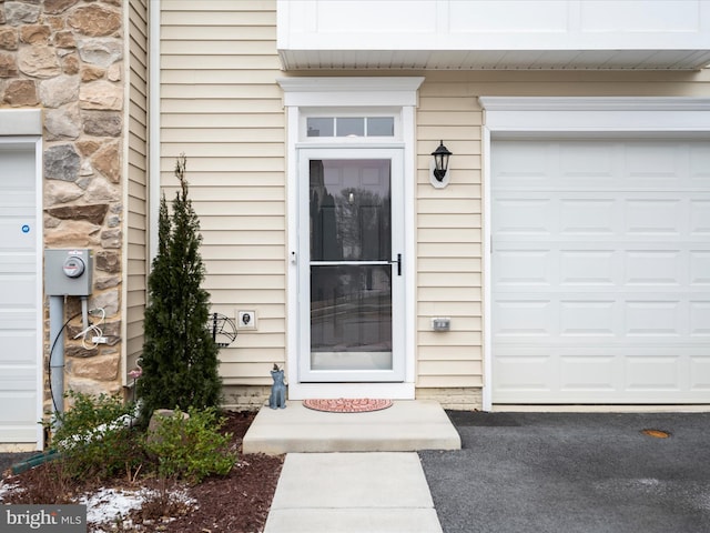 doorway to property featuring a garage and stone siding