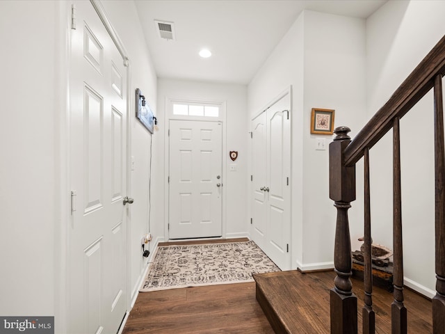 entrance foyer with visible vents, stairs, baseboards, and dark wood-style flooring