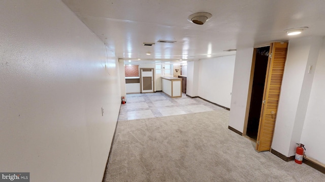 interior space with baseboards, visible vents, and light colored carpet