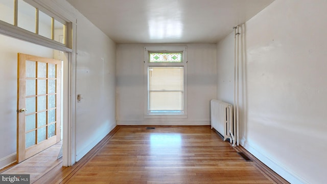 spare room with radiator, light wood-type flooring, and baseboards