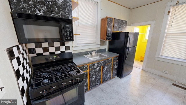 kitchen featuring black appliances, dark countertops, a sink, and visible vents