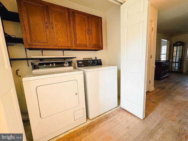 washroom featuring light wood-style floors, cabinet space, and washing machine and clothes dryer