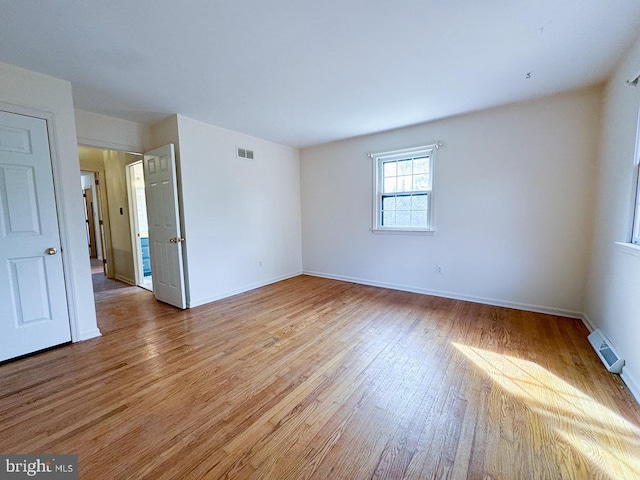 empty room with visible vents, light wood-style flooring, and baseboards