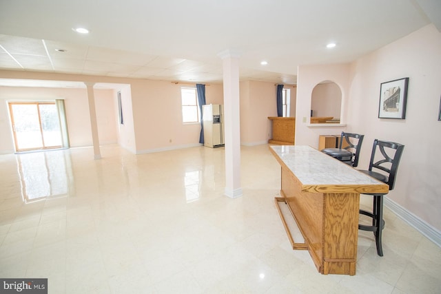 kitchen featuring open floor plan, a kitchen island, a kitchen bar, and baseboards