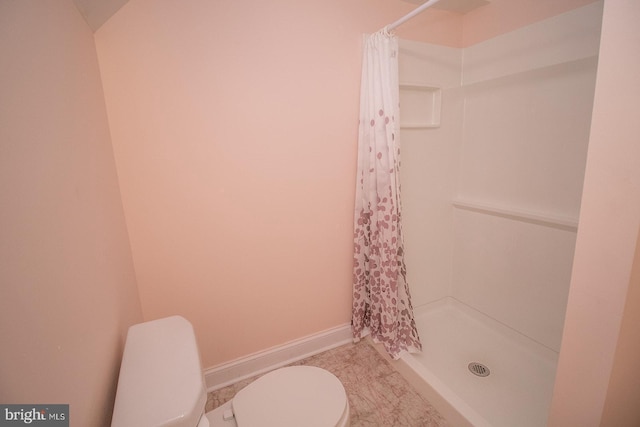 bathroom featuring toilet, a shower stall, and baseboards