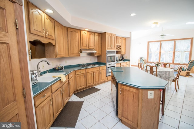 kitchen with a breakfast bar area, under cabinet range hood, a sink, appliances with stainless steel finishes, and a center island