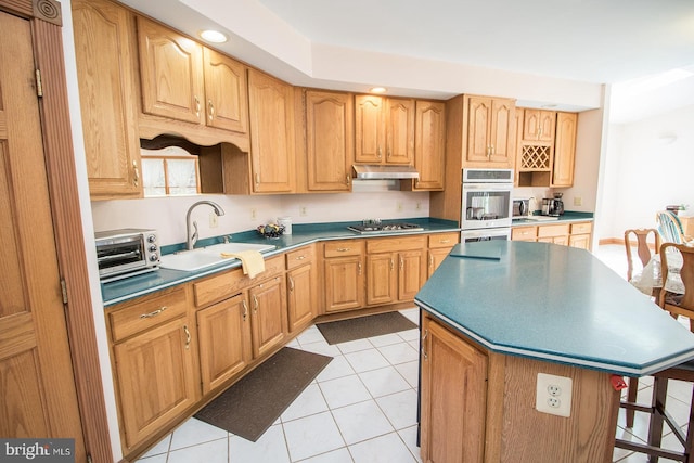 kitchen featuring under cabinet range hood, a toaster, stainless steel appliances, a sink, and a kitchen island