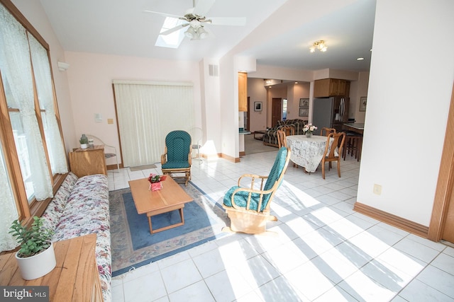 living area with light tile patterned floors, ceiling fan, a skylight, visible vents, and baseboards