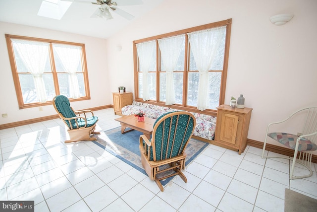 sitting room with vaulted ceiling with skylight, light tile patterned flooring, ceiling fan, and baseboards