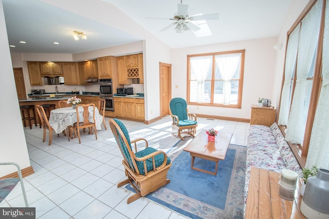 interior space featuring vaulted ceiling, light tile patterned flooring, a ceiling fan, and baseboards