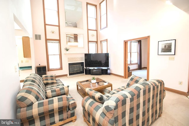 living area with a high ceiling, visible vents, a fireplace, and a wealth of natural light