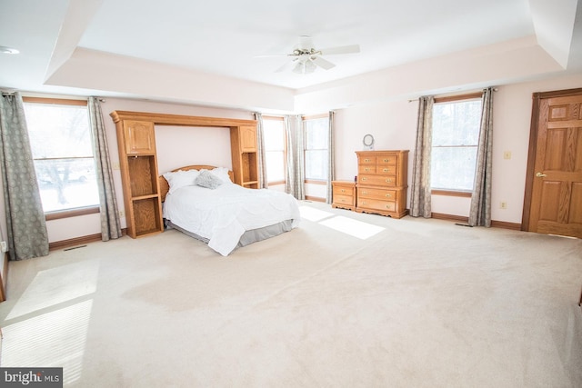 bedroom with baseboards, ceiling fan, a raised ceiling, and light colored carpet