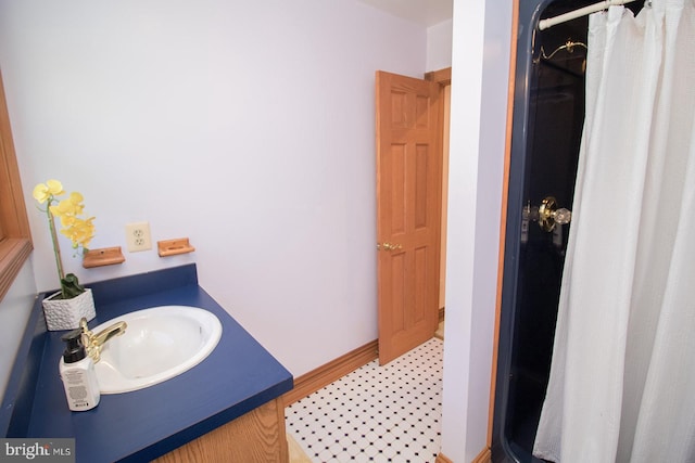 bathroom with a shower with curtain, a sink, and baseboards