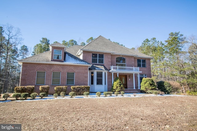 colonial house with brick siding, roof with shingles, and a front lawn