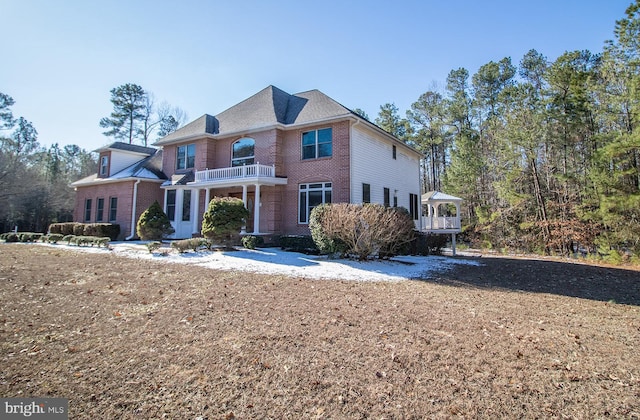 view of front facade with a balcony and brick siding