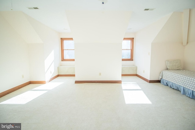 unfurnished bedroom with lofted ceiling, light colored carpet, and visible vents