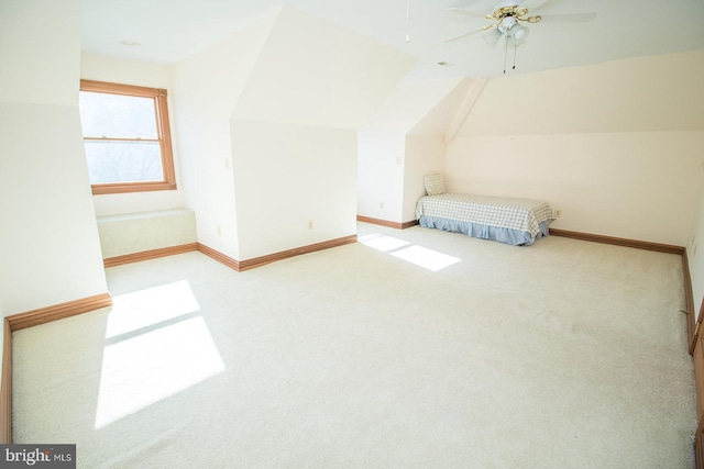 additional living space with light colored carpet, vaulted ceiling, baseboards, and ceiling fan