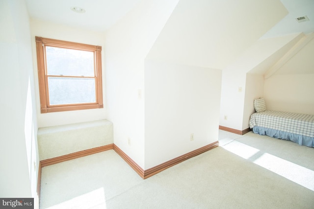 interior space featuring vaulted ceiling, baseboards, visible vents, and light colored carpet