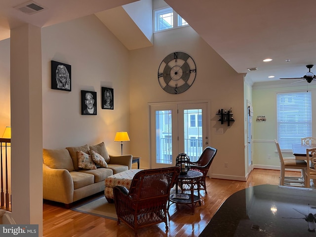 living room featuring baseboards, light wood-style flooring, visible vents, and a healthy amount of sunlight