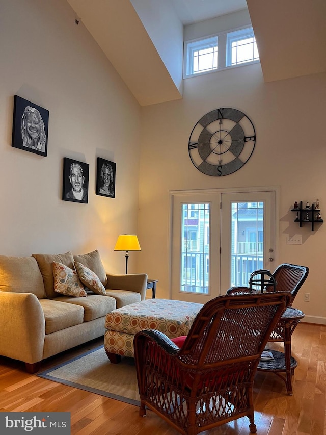 living room featuring a towering ceiling, light wood-style flooring, and baseboards